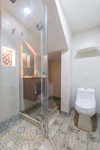 a bathroom with a toilet and a glass shower at Hotel Casa Botero 104 in Bogotá