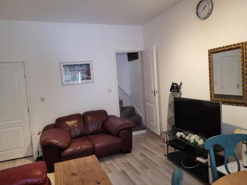 a living room with a leather couch and a mirror at Nice Double Bedroom Near QMC in Nottingham