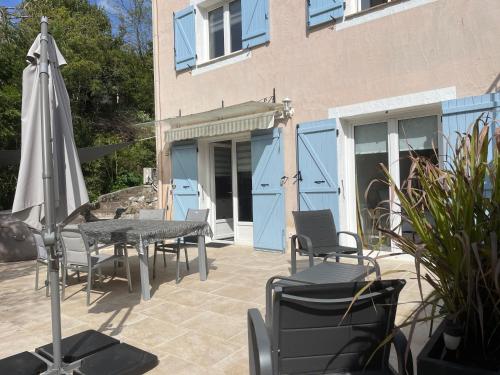 a patio with a table and chairs and an umbrella at LUVA d'Azur, Rez de villa LE RIOU - LE VALLON in Le Bar-sur-Loup