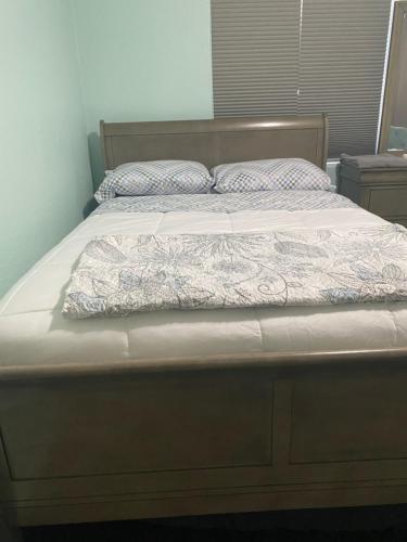 a large bed with a wooden headboard and white sheets at 5821 Gowdy lane bakersfield Ca 93307 in Bakersfield