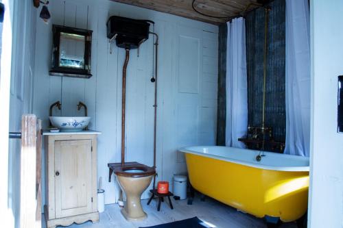 a bathroom with a yellow tub and a toilet at The cabin at Abberley Glamping in Abberley