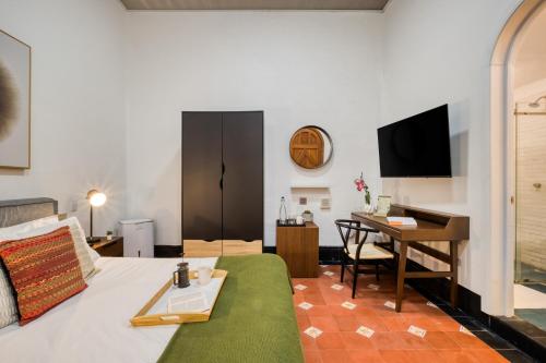 a hotel room with a bed and a desk and a table at Santa Casa by Tasman in Mexico City