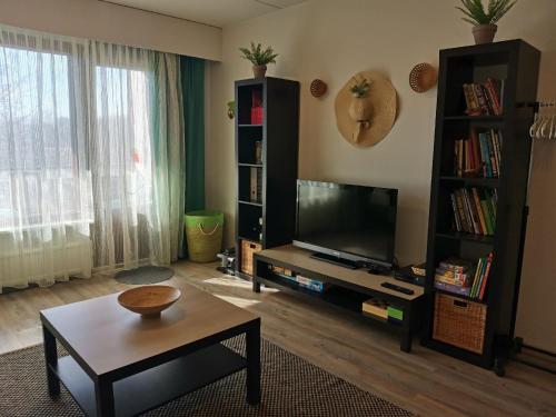 een woonkamer met een flatscreen-tv en een tafel bij Boho Apart Ututie in Kotka