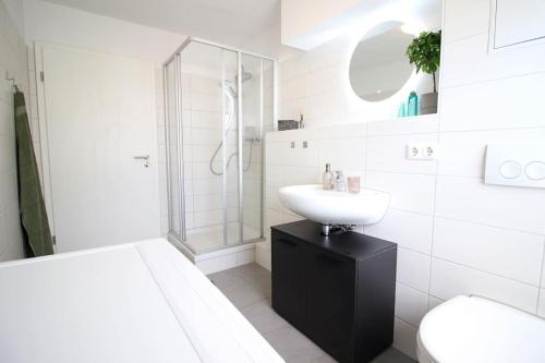 a white bathroom with a sink and a shower at Blossfeld-Apartments XL-Ferienwohnung Jena Zentrum, 2 Schlafzimmer, W-Lan, Waschtrockner, Smart-TV in Jena