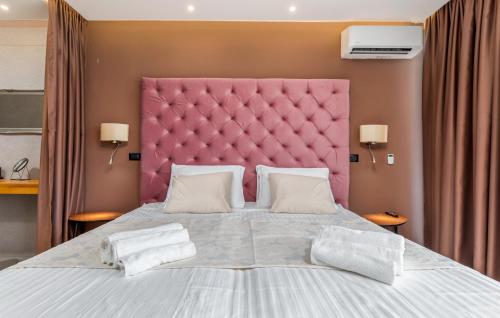 a bedroom with a large bed with a pink headboard at Villa Grande Arche Istria in Ližnjan