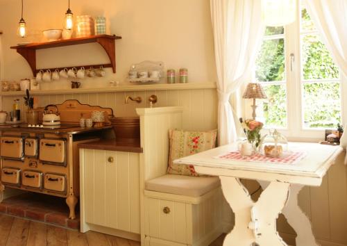 a kitchen with a white table and a stove at Weißt Du noch - Gästehäuser & Suiten in Kühlungsborn