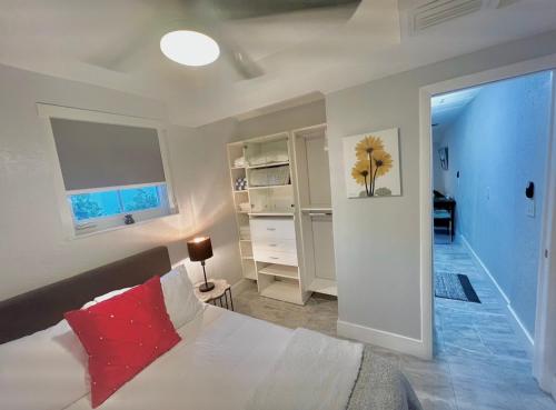une chambre avec un lit blanc avec un oreiller rouge dans l'établissement Little Gables Studio-Your Miami Escape-10min Airport, à Miami