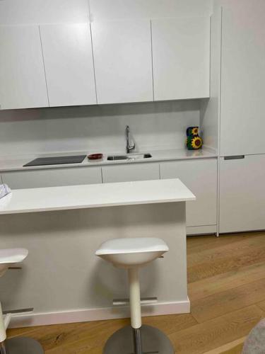 a kitchen with white cabinets and a sink and a stool at preciosa casa,garage wifi 4 personas in Vigo