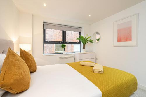 a bedroom with a bed with yellow sheets and a window at Oxford Street - Mayfair in London