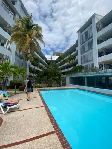 a person in a chair next to a swimming pool at Palms And Poolside Paradise #403 in San Juan