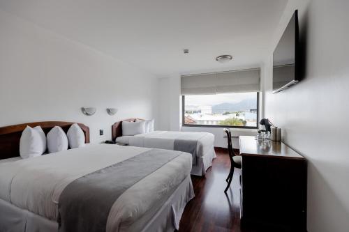a hotel room with two beds and a flat screen tv at Parque del Lago Boutique Hotel in San José