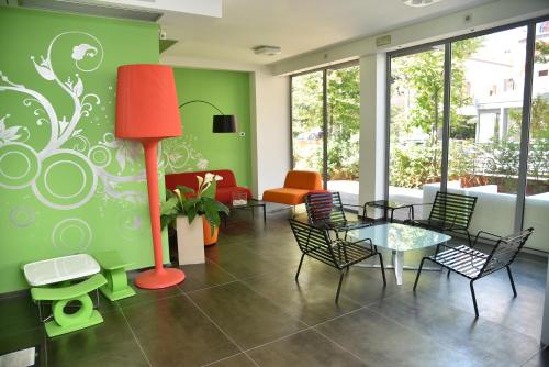 a living room with a red floor lamp and chairs at Sound Suite Hotel in Riccione