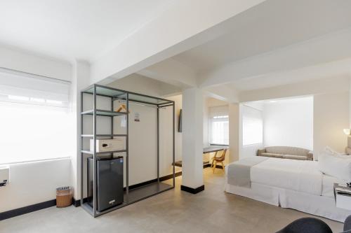 a white bedroom with a bed and a desk at Parque del Lago Boutique Hotel in San José