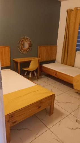 Zimmer mit 3 Betten, einem Tisch und einem Stuhl in der Unterkunft T3 VILLA DAGONI LOGONI in Koungou