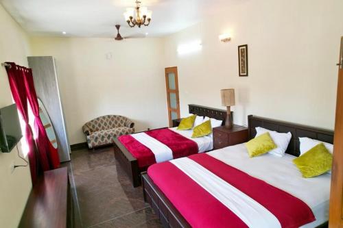 a hotel room with two beds and a chair at Forest View Resort in Yercaud