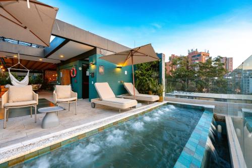 a pool with chairs and an umbrella on a building at Celestino Boutique Hotel in Medellín