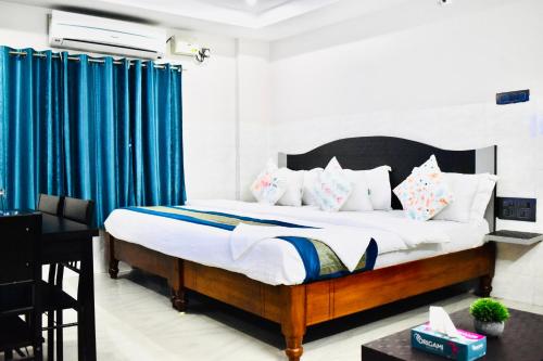 a bedroom with a large bed with blue curtains at Hotel Unique Stays in Rājampet