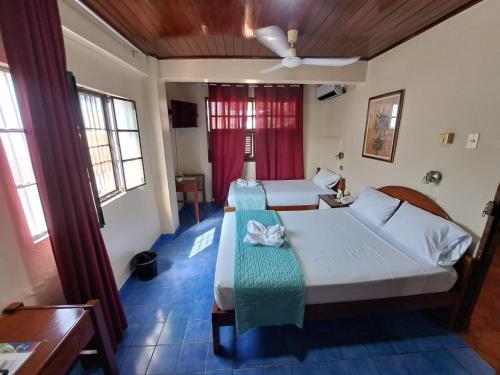 Hotel Virrey Pucallpa EIRL في بوكالبا: غرفة نوم بسريرين ومروحة سقف