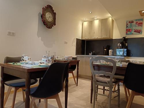 a kitchen with a table with chairs and a clock on the wall at L'ancienne forge 3 chambres d'hôtes à l'étage la forge , l'enclume et le marteau in Louvetot