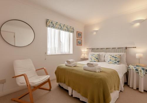 een slaapkamer met een bed, een stoel en een spiegel bij Ballard View Apartment in Swanage