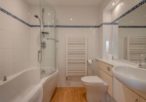 a bathroom with a tub and a toilet and a sink at Ballard View Apartment in Swanage