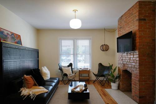 a living room with a black couch and a brick fireplace at Beautiful Home Central Columbus in Columbus
