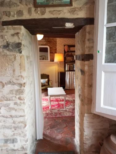 une porte menant à un salon avec un mur en pierre dans l'établissement L'ancienne épicerie, à Le Cercueil