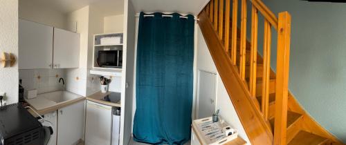 a small kitchen with a staircase with a blue curtain at Appartement cosy vue port in Dives-sur-Mer
