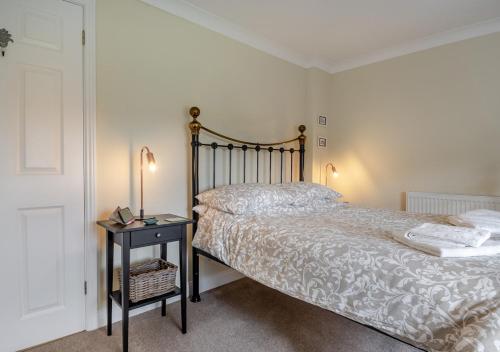 a bedroom with a bed and a table with a night stand at Honeysuckle in Halesworth