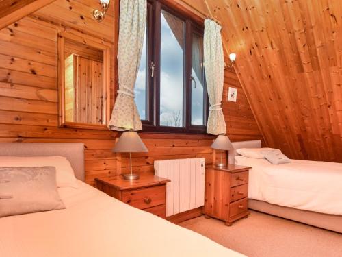 a bedroom with two beds in a log cabin at 2 bed in Launceston TWIME in Saint Clether