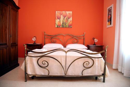 a bedroom with a bed with an orange wall at B&B Borgosolare in Specchia
