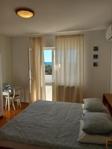 a bedroom with a bed and a table and a window at Sobe Ruža in Banjol