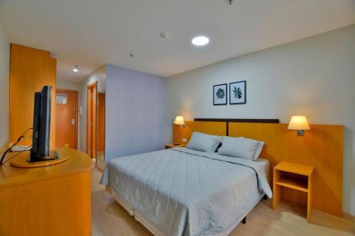 Comfort Hotel Taguatinga - Flat Preferido c/ Wifi في برازيليا: غرفة نوم بسرير وتلفزيون بشاشة مسطحة