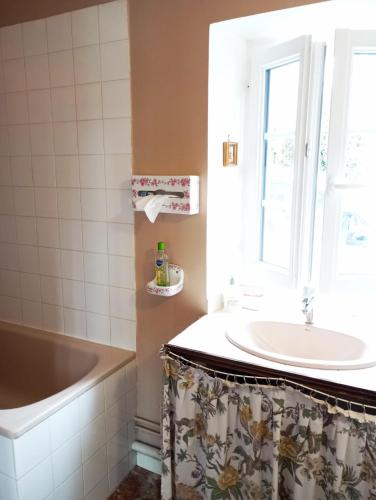 une salle de bain avec une baignoire, un lavabo et une fenêtre dans l'établissement L'ancienne épicerie, à Le Cercueil