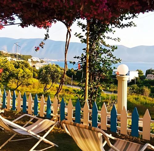 two chairs and a fence with mountains in the background at Hotel Sirena in Vlorë