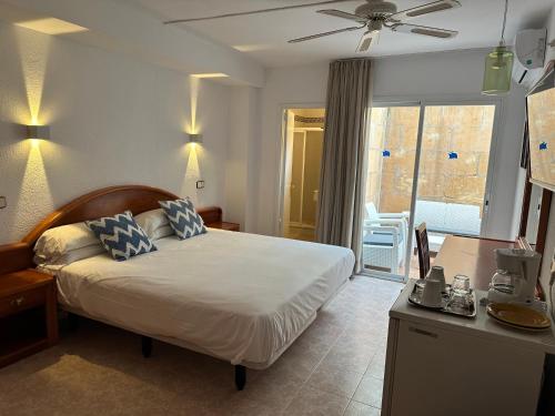 a bedroom with a bed and a desk and a window at Hostal de la Caravel-la in Cala d´Or