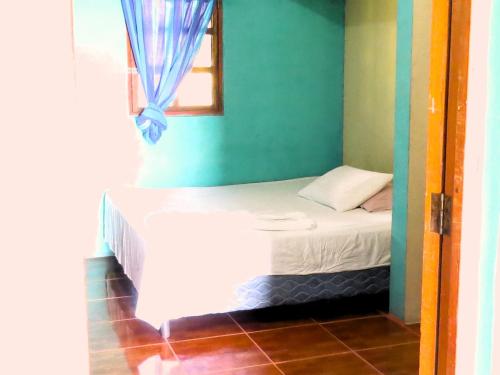 uma pequena cama num quarto com uma janela em Casa Reyna em Moyogalpa
