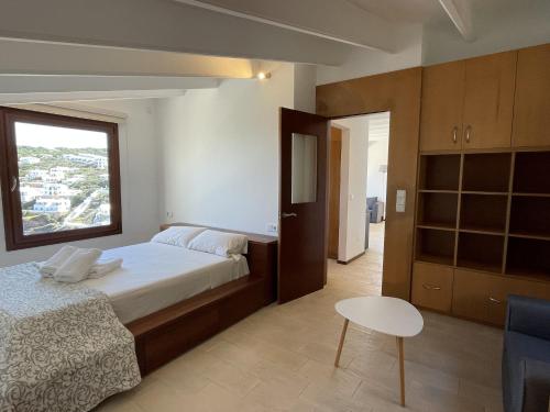 um quarto com uma cama, uma mesa e uma janela em Apto. Ses Ancolles Vistas Mar em Cala Morell
