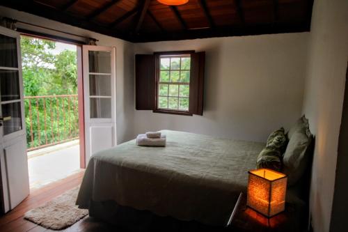 a bedroom with a bed with a lamp and a window at Casa da Vila in Tiradentes