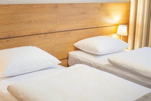 two beds in a hotel room with white pillows at NOVY Hotel in Zielona Góra
