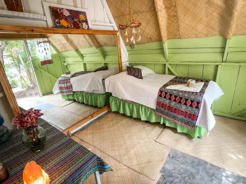 a bedroom with two beds in a room with green walls at Unicorn Reborn - Peaceful Rentals in San Marcos La Laguna