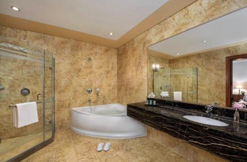 bagno con vasca e grande specchio di Al Raha Beach Hotel - Superior Room DBL - UAE a Abu Dhabi