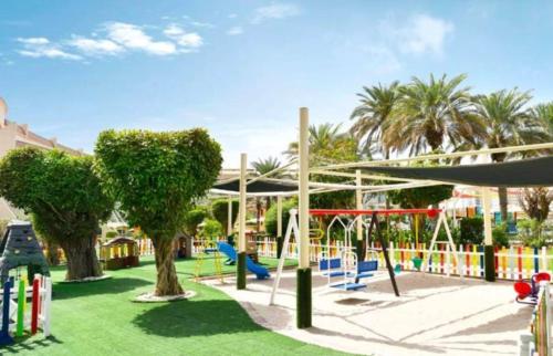 un parque con un parque infantil con árboles y columpios en Al Raha Beach Hotel - Superior Room DBL - UAE en Abu Dabi