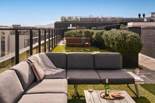 都柏林的住宿－Sonder at Britain Quay，阳台的沙发、桌子和一瓶葡萄酒