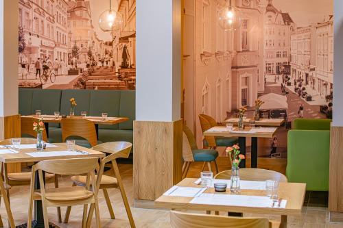 a restaurant with tables and chairs and a mural of a city at NOVY Hotel in Zielona Góra