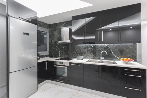 a kitchen with black cabinets and a stainless steel refrigerator at Marina Apartments in Kardamili