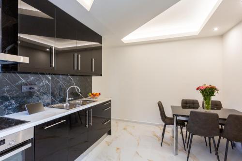 a kitchen with black cabinets and a table with chairs at Marina Apartments in Kardamili