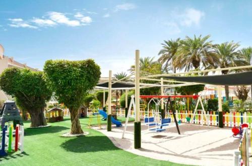 einen Spielplatz mit Schaukeln und Bäumen in einem Park in der Unterkunft Al Raha Beach Hotel - Gulf View Room SGL - UAE in Abu Dhabi