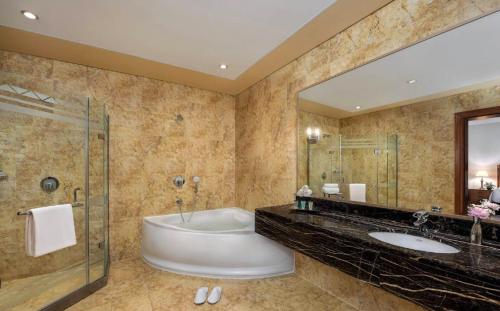 La salle de bains est pourvue d'une baignoire, de 2 lavabos et d'une douche. dans l'établissement Al Raha Beach Hotel - Gulf View Room SGL - UAE, à Abu Dhabi