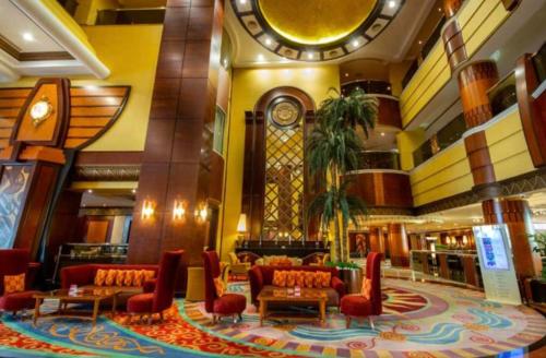 a lobby with couches and a clock in a building at Al Raha Beach Hotel - Gulf View Room SGL - UAE in Abu Dhabi